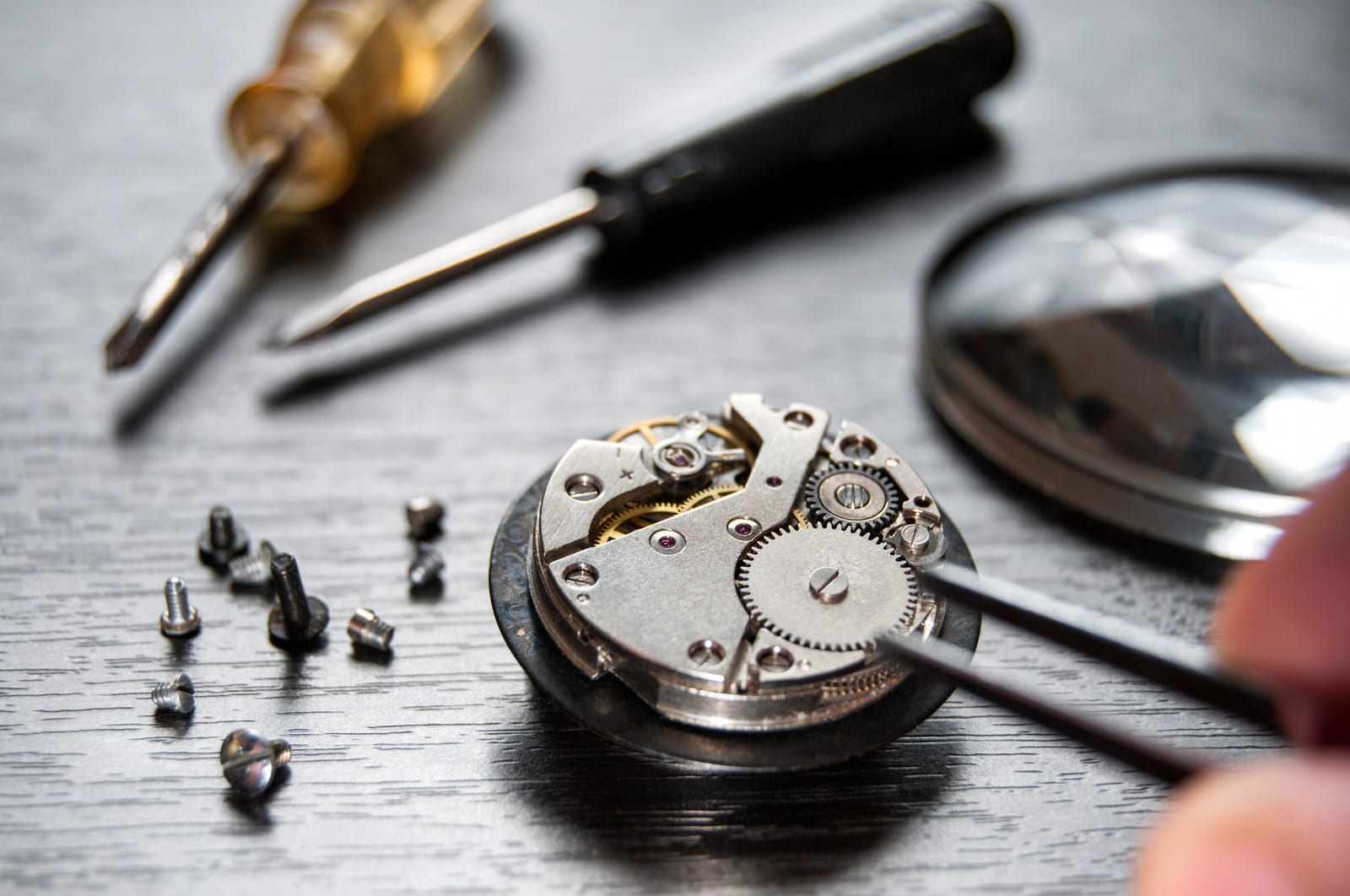 Attrezzi da orologiaio e movimento aperto su un banco di lavoro